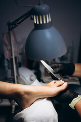 Close-up of female foot during hygienic pedicure under lamp light.