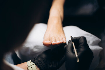 Close-up of female foot during hygienic pedicure under lamp light.