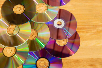 Compact discs lying on a wooden table in bright sunlight, CDs with sun reflections on wooden background, computer compact discs in sunlight.