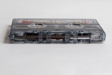 Audio cassette with magnetic tape lying on white background close-up, brown magnetic tape in audio cassette for analog sound recording, audio cassette super close-up.