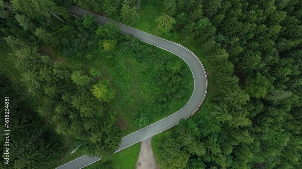 Poster road with a sharp bend in the middle of the forest. downhill from a drone view