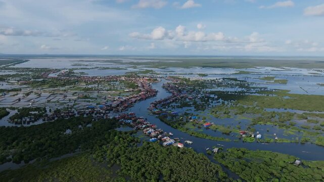 Wide aerial view of Tonl&eacute; Sap flooded plains with clustered floating villages and green forest.