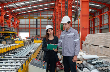 Two worker with safety helmet and black suit standing in a factory, holding clipboard, used for taking note, check schedule and review document.