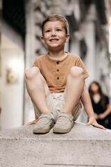 Smiling child sitting on a low wall in genoa, italy, exploring the city with family