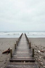 Obraz premium Serene Coastal Wooden Pathway Leading to the Ocean on a Cloudy Day