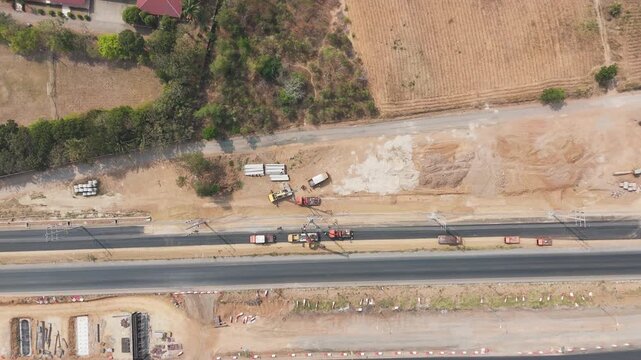 Drone footage aerial view scenic landscape Cranes and mechanics repair high-voltage power lines along a rural road under construction 