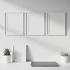 Minimalist workspace with three empty white frames on the wall, two green potted plants, and a silver laptop on a clean desk.