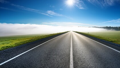 Naklejka premium foggy haze blankets the landscape as the empty road stretches towards the horizon under a bright blue sky