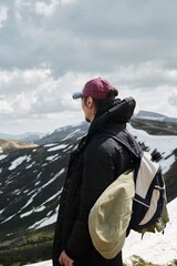 Man standing on snowy mountain, carrying snowboard and backpack