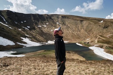 Man standing on mountain overlooking scenic lake in Ukraine