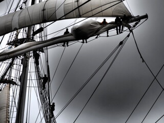 dramatic black and white of sailors furling a sail