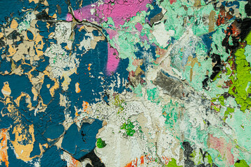 Abstract: crumbling graffiti on a city street wall. Colorful abstract background. Old, cracked, peeling paint serves as a background.