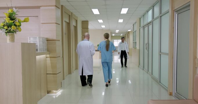 doctors and nurses walking inside hospital corridor during busy work shift while one staff checking patient record at counter showing active healthcare teamwork during emergency care situation