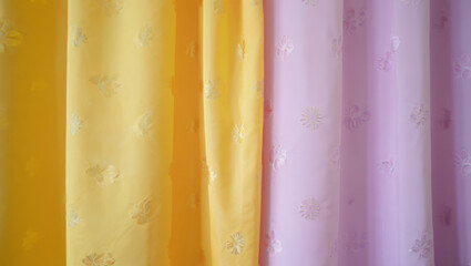 Soft yellow and purple fabric drapes with delicate gold floral embroidery
