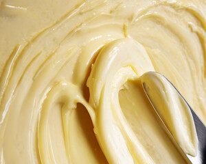 Close-up of creamy butter or margarine being smoothly spread with a butter knife