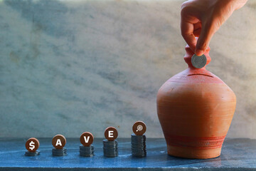 Hand putting a coin into a Soil Bank with the word SAVE
