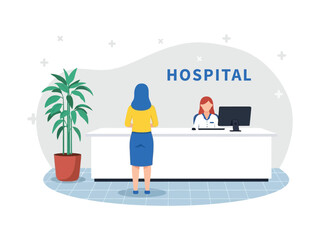 A woman stands at a hospital reception desk, checking in with the female receptionist.