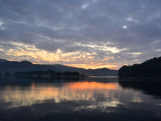 Fototapeta premium Sunset over the estuary with the sky covered by a dense layer of stratocumulus and nimbostratus clouds. 