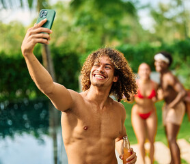 Young people having fun dancing and drinking and bonding listening to music at a party by pool in a...
