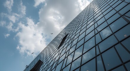 Modern skyscraper facade reflecting a partly cloudy sky.