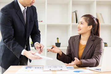 Two Asian business people with analyzing financial report working together in office.