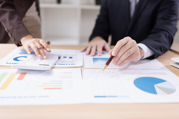Asian businesswoman and businessman with paper documents financial analysis data charts in office working space.
