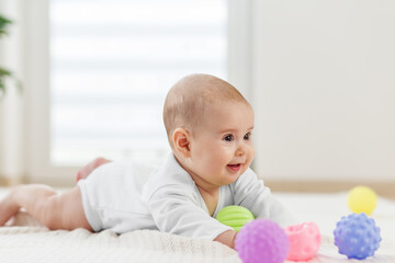 Smiling baby playing with colorful sensory balls. Baby care.