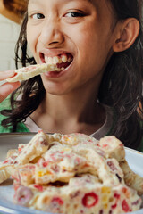 Indonesian teenage girl biting soft and chewy homemade marshmallow nougat for Christmas dessert