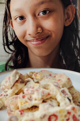Southeast Asian young girl smiling while proudly showing her homemade sweet marshmallow nougat using her own recipe
