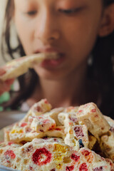 Southeast Asian teenage girl eating a plate of full soft and chewy homemade marshmallow nougat cookies for snack