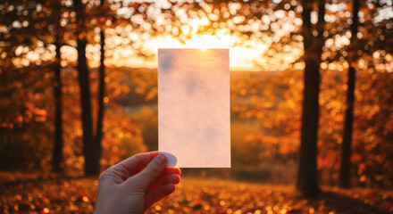 Blank paper held in hand against an autumnal backdrop.