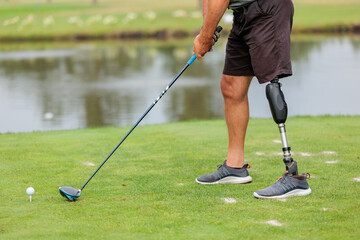 golfer with prosthetic leg hitting with putter on golf ball during golfing. Concept of willpower of people with disabilities in sport