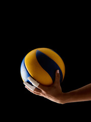 Hand grasping volleyball against black background with tape-wrapped fingers. Concept of upright...