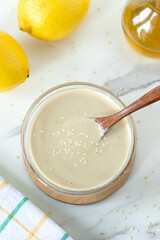Tahini lemon white pasta sauce in a bowl with wooden spoon. Top view.
