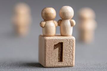 Two wooden figures stand on a block marked 1 with blurred figures in the background
