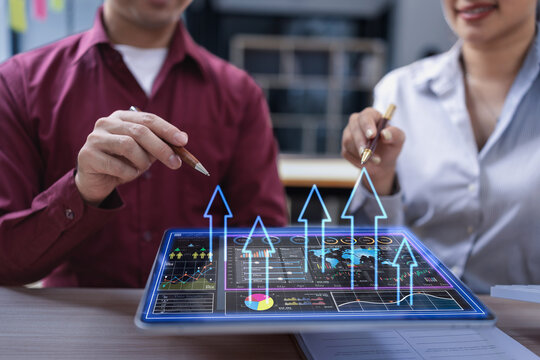 Businessman and woman holding digital tablet with futuristic interface for analytics data dashboard.