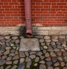 An old downpipe on the wall of a brick building.