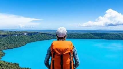 Fototapeta premium Exploring breathtaking vistas with a bright blue lake under the expansive sky and a hiker in a vibrant backpack