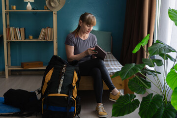 Senior woman planning trip with a checklist preparing things for backpack. Travel, planning and...
