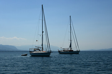Fototapeta premium Sailing Boats Anchored on a Calm Sea with Mountains in the Background