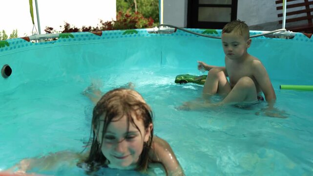 Cute game of brother and sister in the pool. Summer, vacation, enjoyment, fun. Boy with Down syndrome. Inclusion, family. 