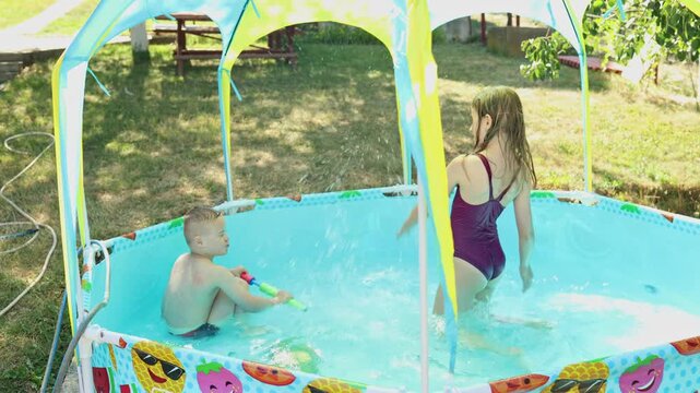 Funny summer pool fight. A girl and her younger brother with Down syndrome enjoy swimming in a small pool. Real authentic family moments. Vacation. 