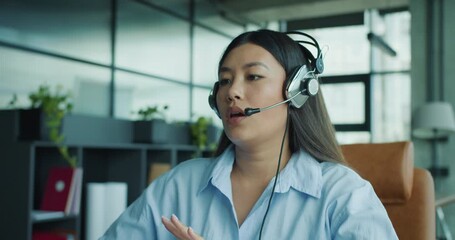A young woman in a headset is engaged in a meaningful conversation in a modern office, using technology effectively