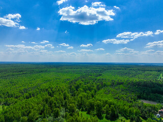 An aerial view captures a vast expanse of lush green forest and open fields stretching to the...