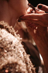 Fashion shot of makeup artist doing brown lips with a brush, make up visage process