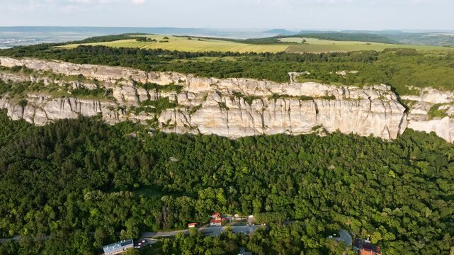 Aerial view showing majestic Madara Rider UNESCO site carved in limestone cliff near Madara village, Bulgaria, summer landscape, historical monument surrounded by forests, hills, and countryside
