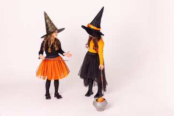 Two little girls in witch costumes having fun on Halloween on white background with copy space....