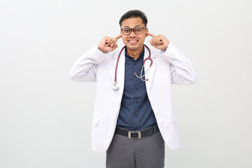 Handsome adult doctor man wearing doctor's suit over isolated background covering ears with fingers...