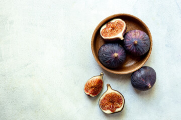 Fresh ripe figs on a wooden bowl top view on a stone background