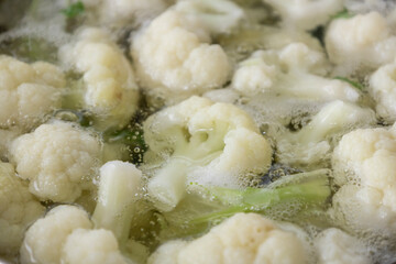 Fresh cauliflower is boiled in a saucepan with water. The vegetable is divided into florets and boiled in a saucepan.